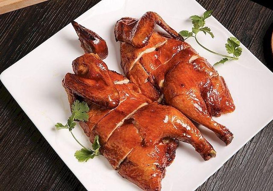 Two whole Guan Chee roast chickens on a white platter